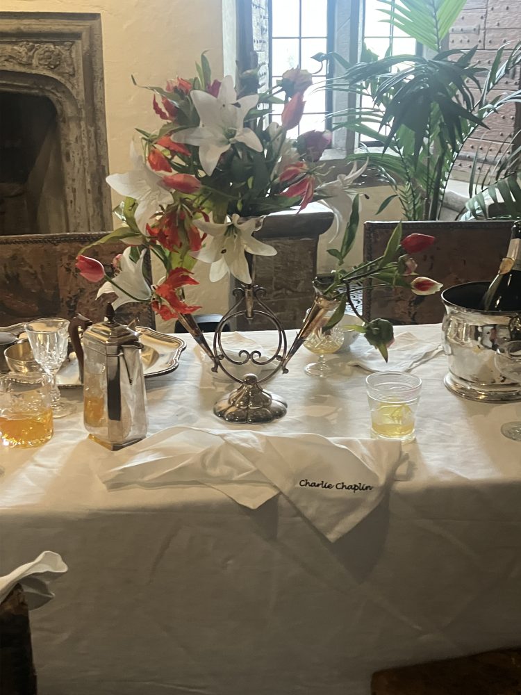 Table décorée avec vase de fleurs d'amarilys, serviette brodée avec le nom Charlie Chaplin.
