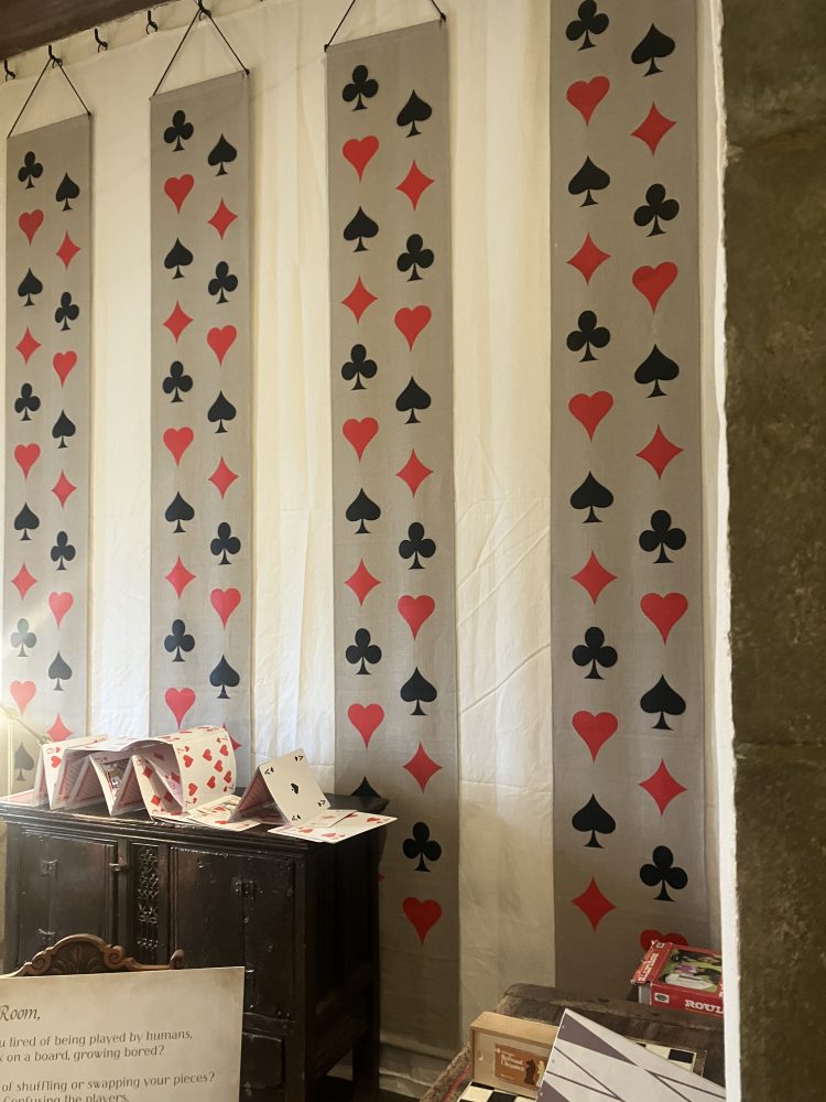 Salle de jeux. Panneaux rectangulaires accrochés aux fenêtres. Symbole des cartes dessiné dessus. Meuble avec montage de cartes