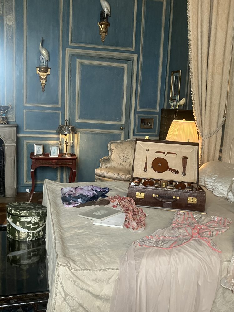 Lit avec draps blancs en soie. Valise avec produits de toilettes ouverte. Vêtements sur le lit